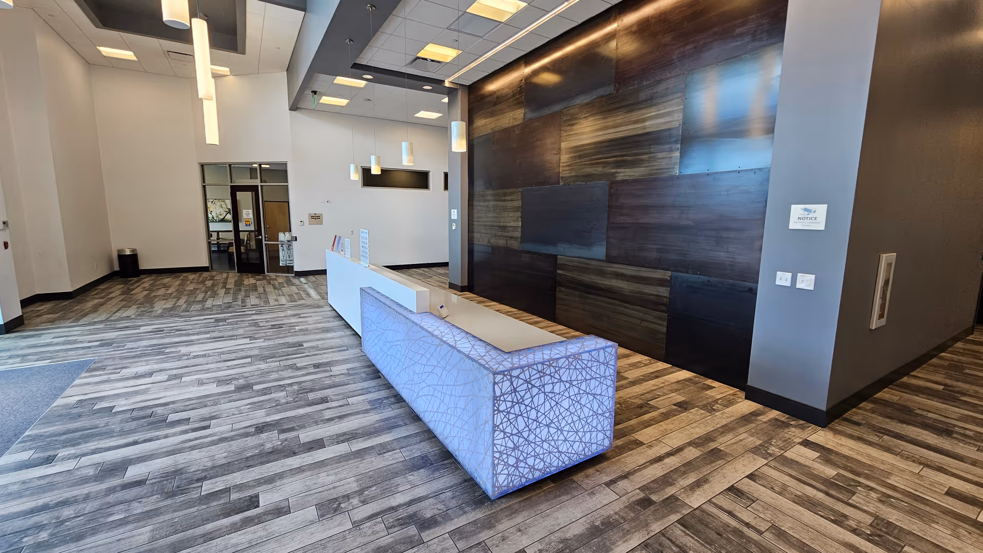 Modern interior lobby featuring a long patterned reception desk and dark wood wall panels.