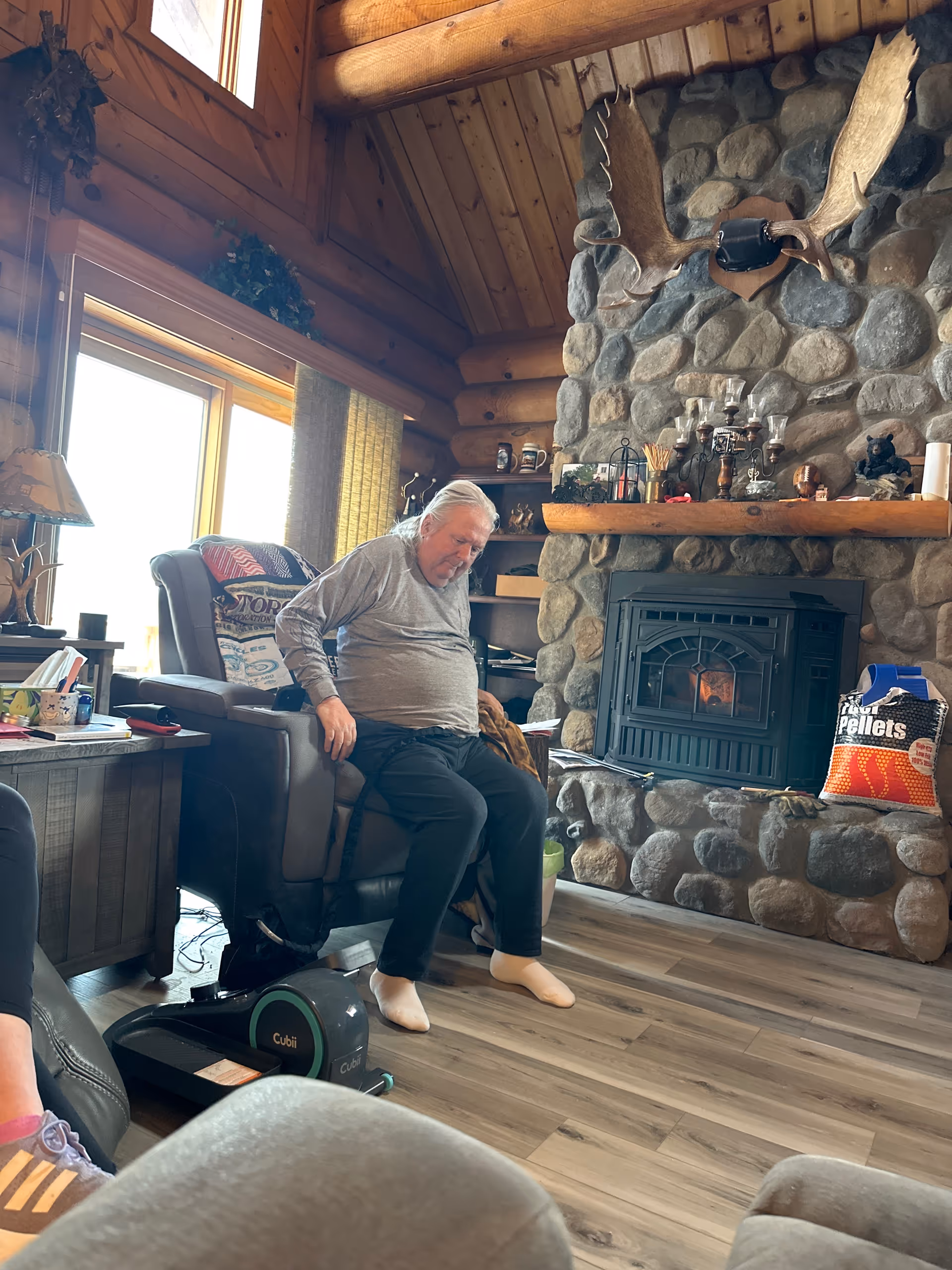Senior man relaxing in a rustic living room with stone fireplace.