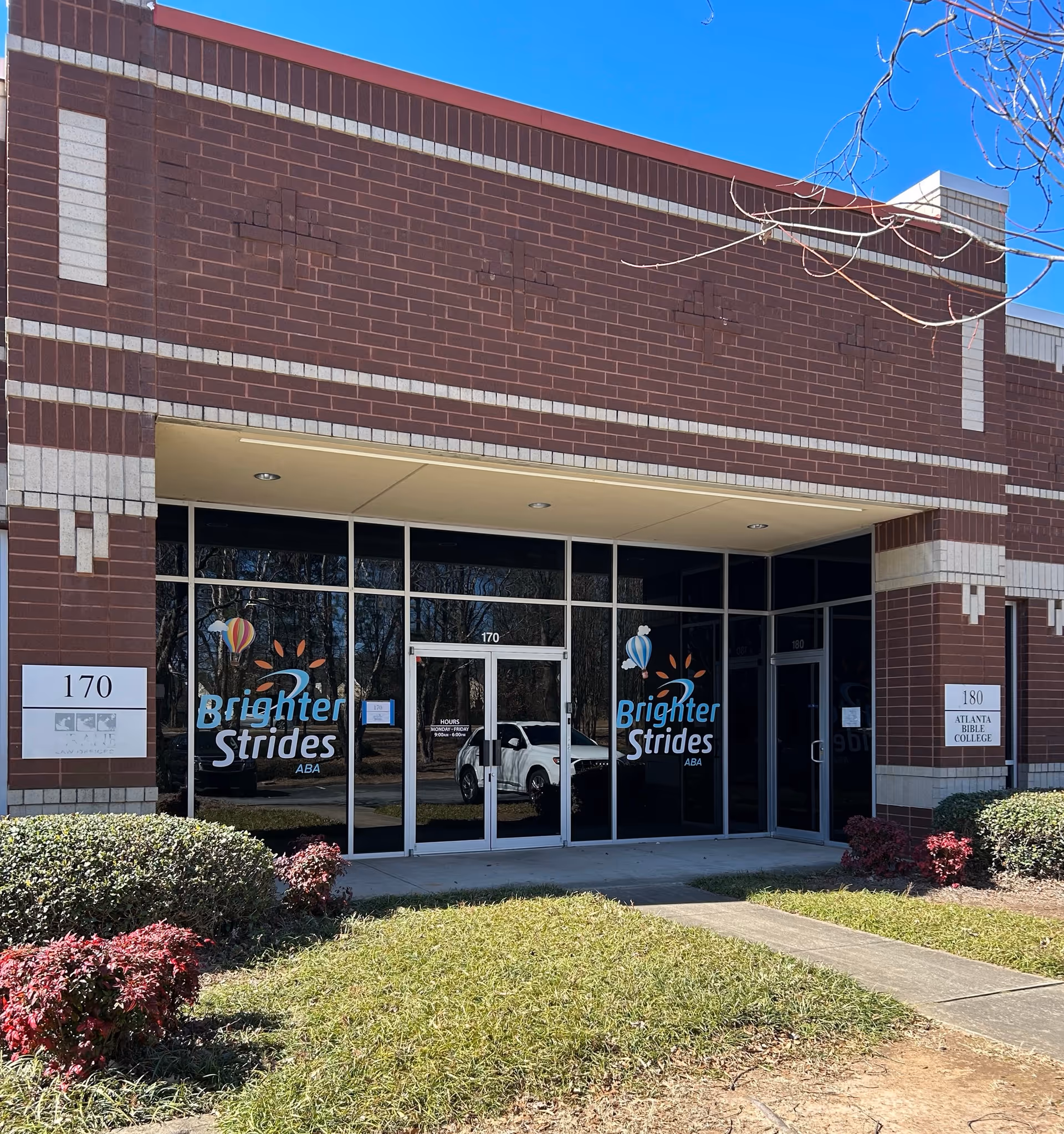 Brick building front with glass doors labeled Brighter Strides ABA Therapy, landscaped entrance.