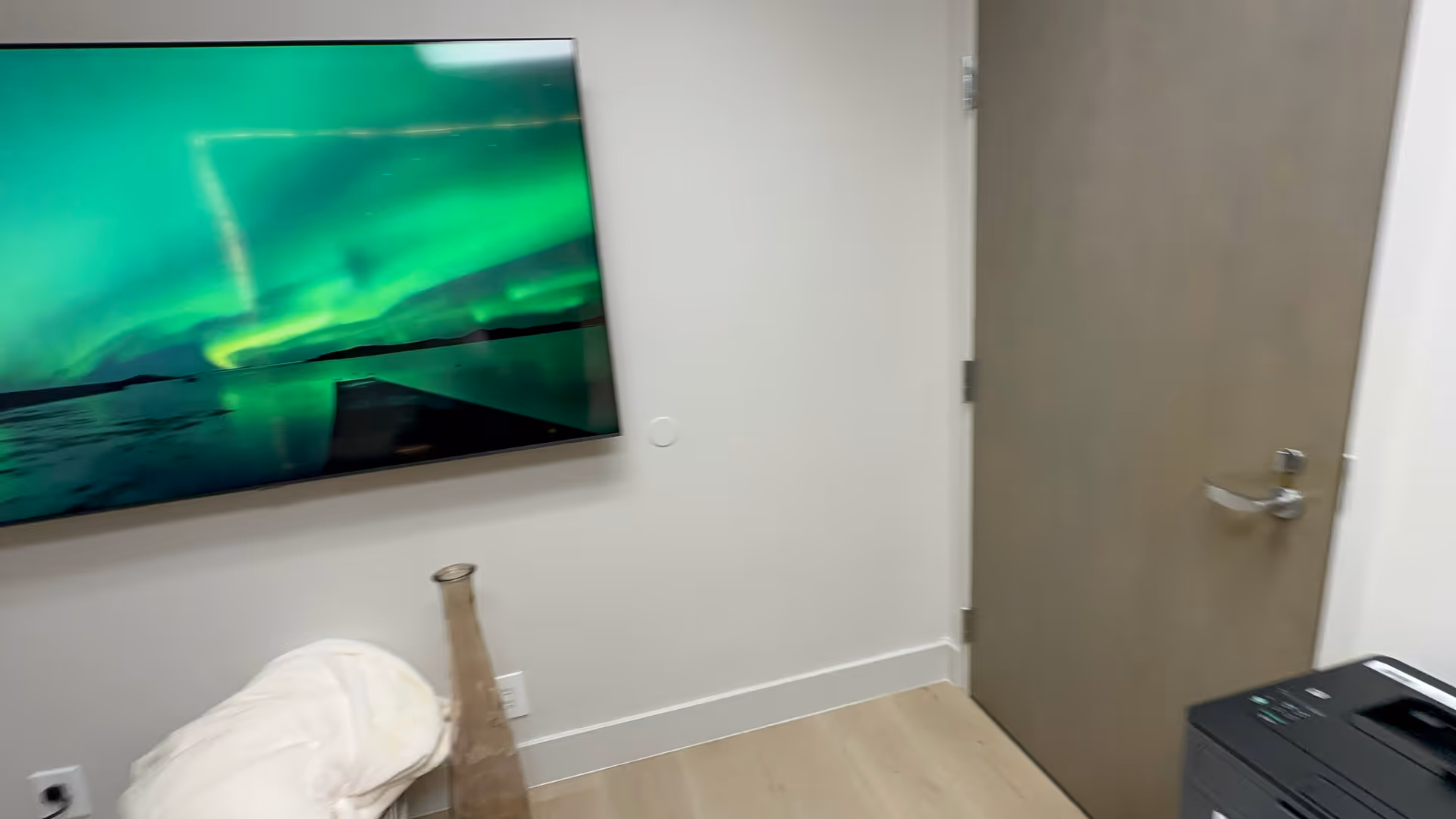 Wall-mounted TV shows aurora borealis in a clean, modern interior.