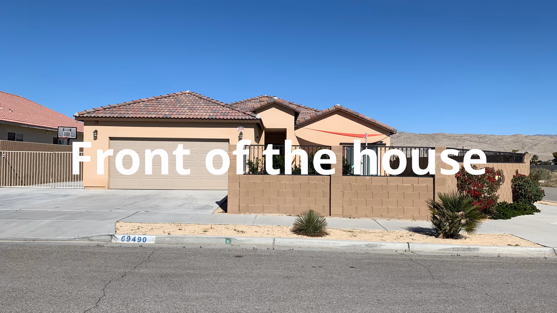 Front view of a tan suburban house with a brick wall and driveway.