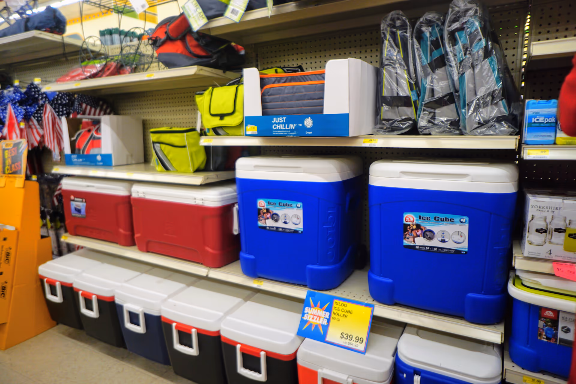 Indoor store aisle displaying large blue and red coolers and assorted gear.