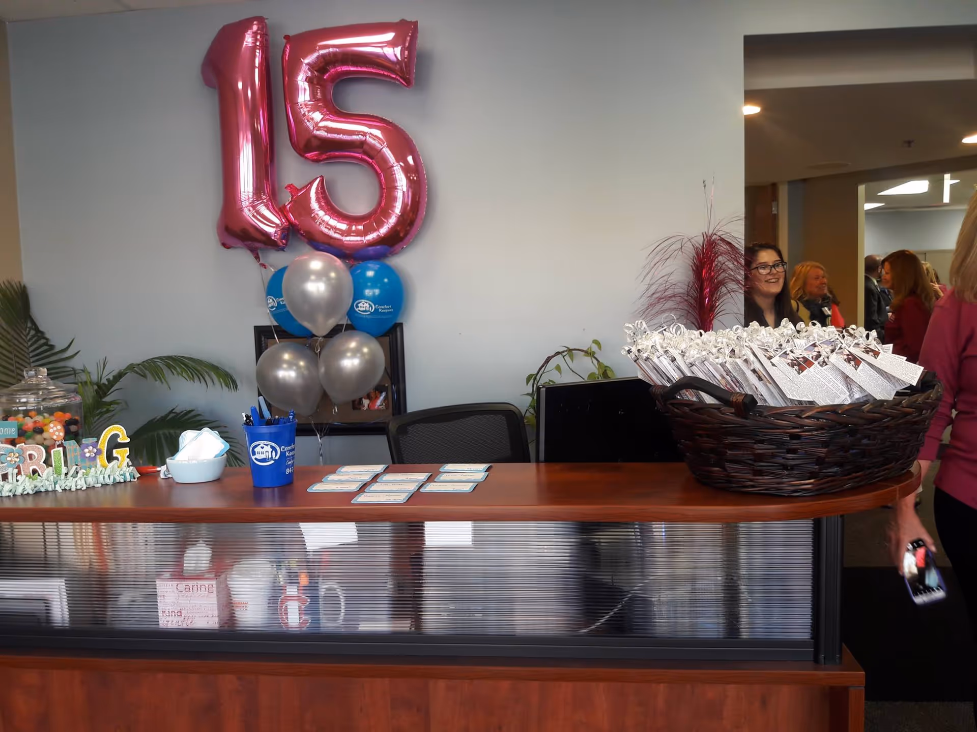 Lobby reception desk with pink 15 balloons and gift baskets inside a Comfort Keepers facility.