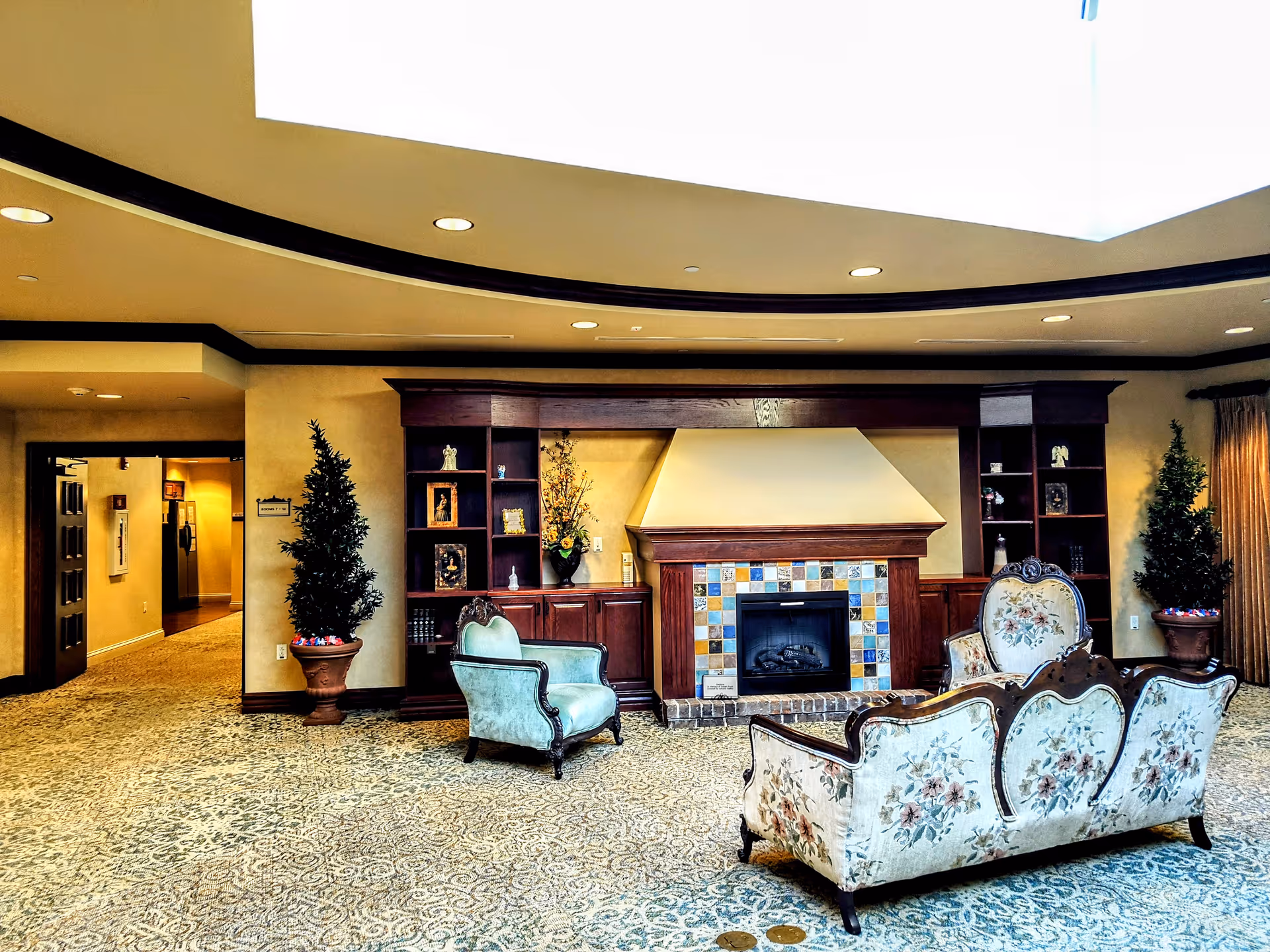 Luxurious lobby seating area with fireplace, shelves, plants, and patterned carpet.