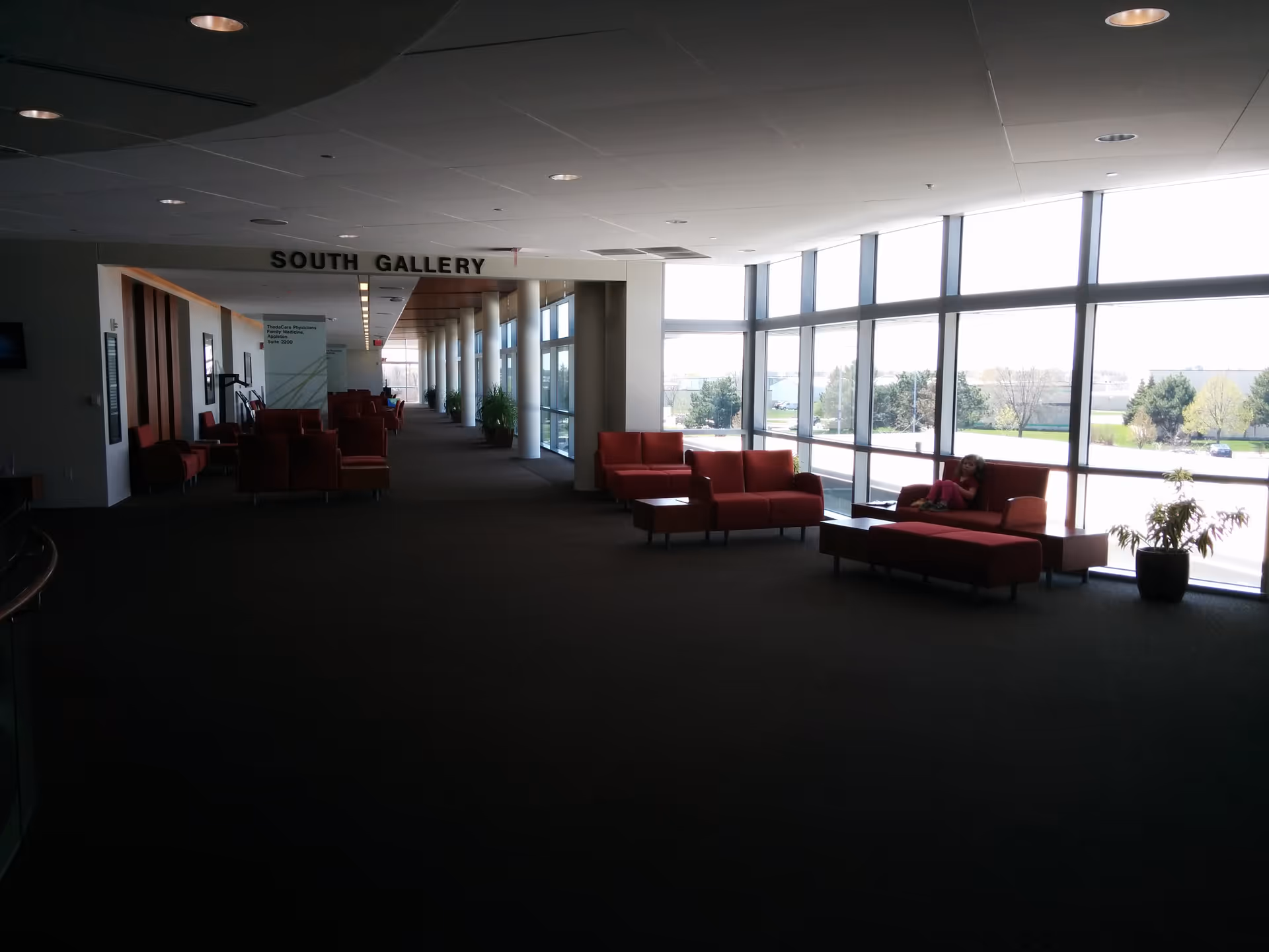 Long interior hallway with red seating, large windows, and a 'South Gallery' sign.