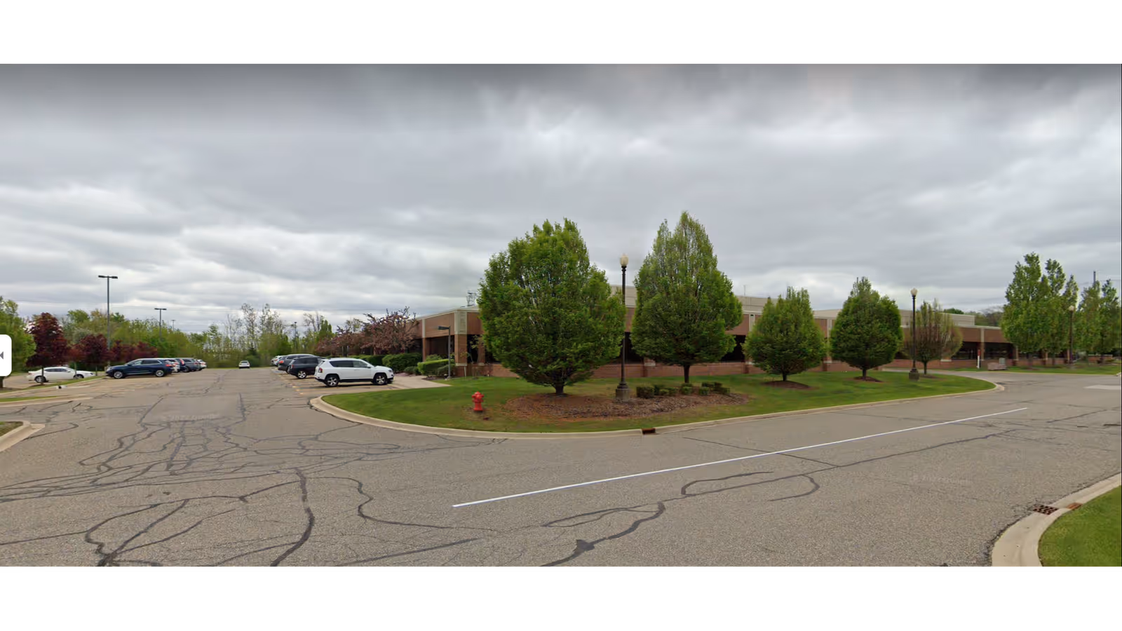 Exterior view of a Soleo Health building with trees, parking lot, and cloudy sky.