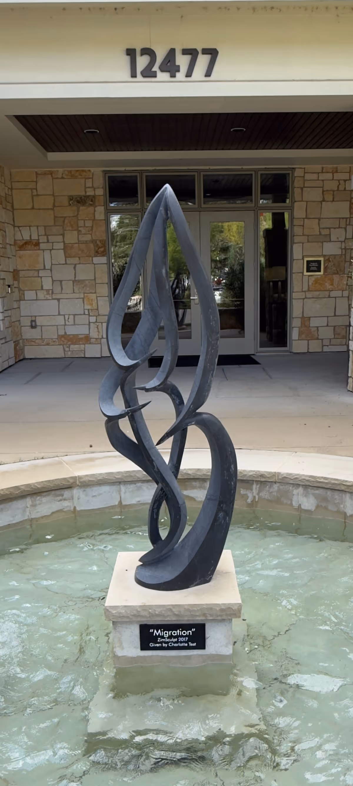 Front entrance of Faith Presbyterian Hospice with a twisting metal sculpture in a fountain.