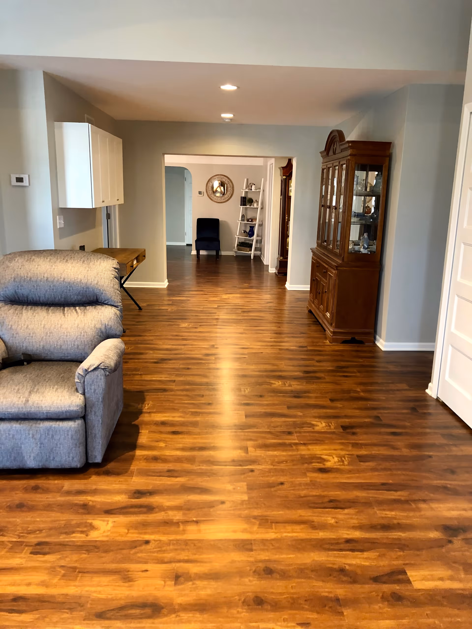 Open living area with hardwood floor, gray sofa, and a doorway to another room.
