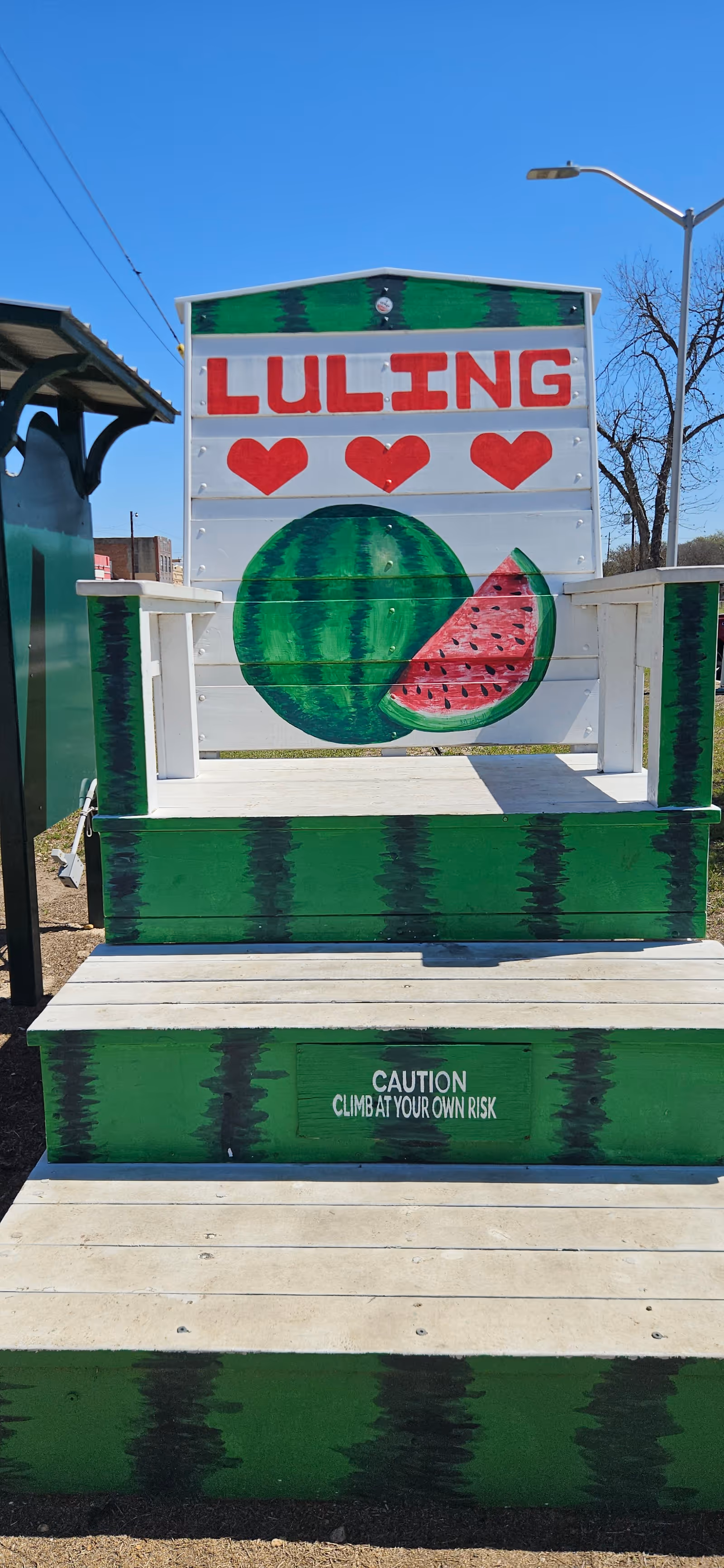 Outdoor wooden stairs with a watermelon sign and caution text reading Climb at your own risk