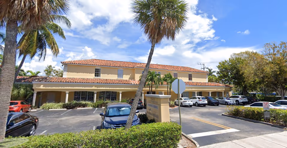Front exterior view of Senior Helpers building with palm trees and a parking lot.