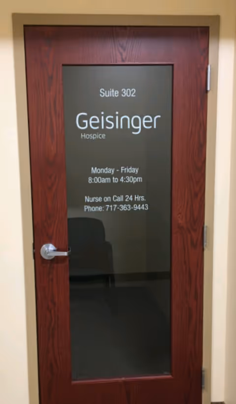 Wooden door with frosted glass panel displaying Geisinger Hospice Suite 302 signage.