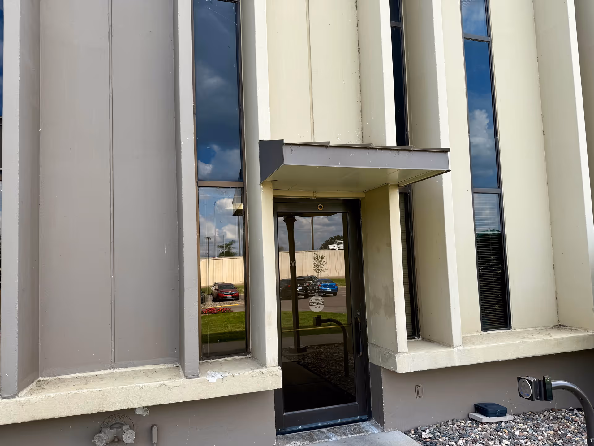 Front entrance of a modern building with glass doors and tall windows.