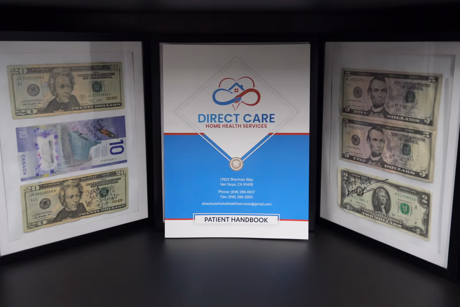 Three framed displays show currency on the sides with a Direct Care Handbook center stage.
