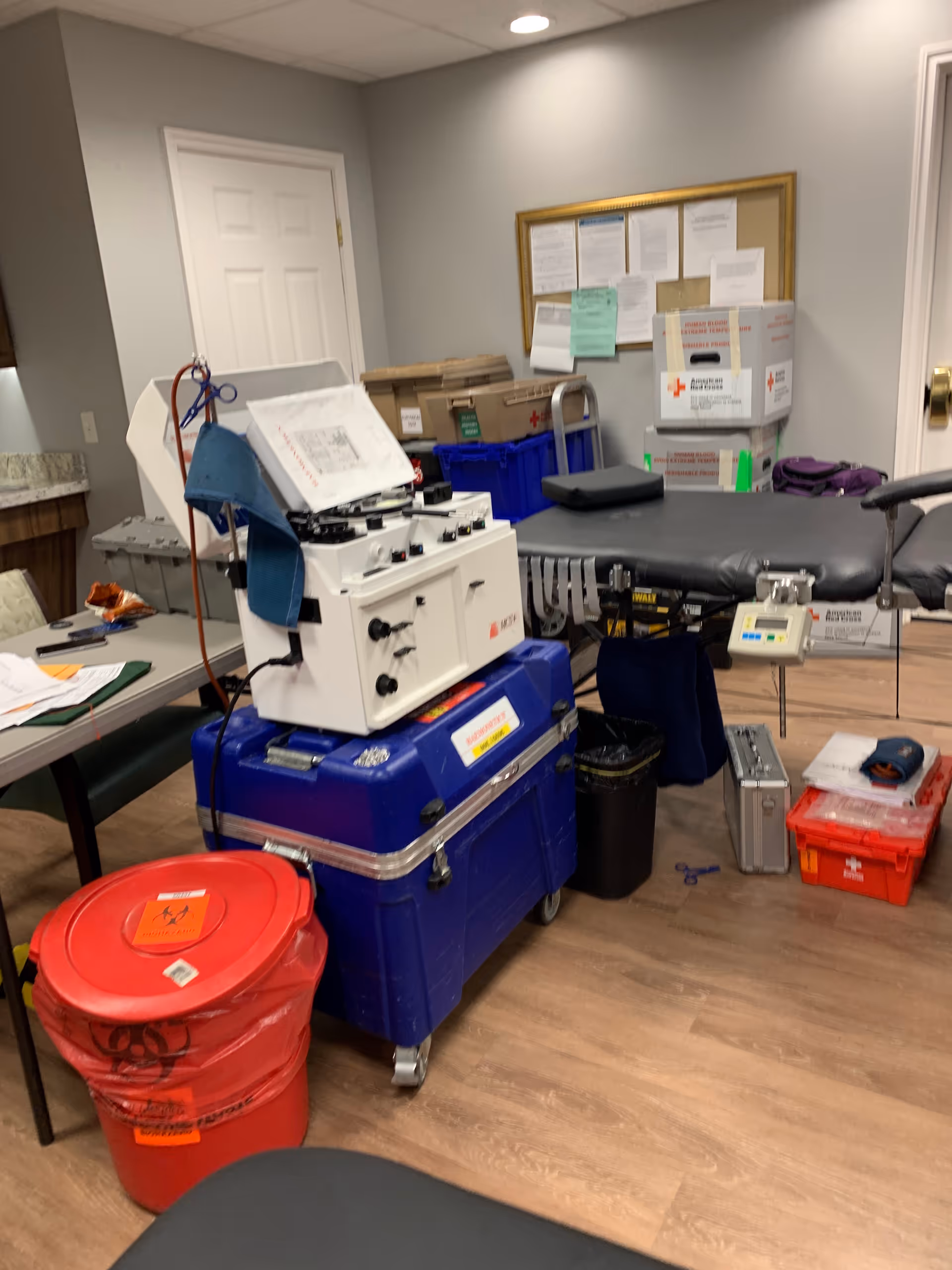 Medical equipment and a treatment table fill a clinic room with storage boxes.