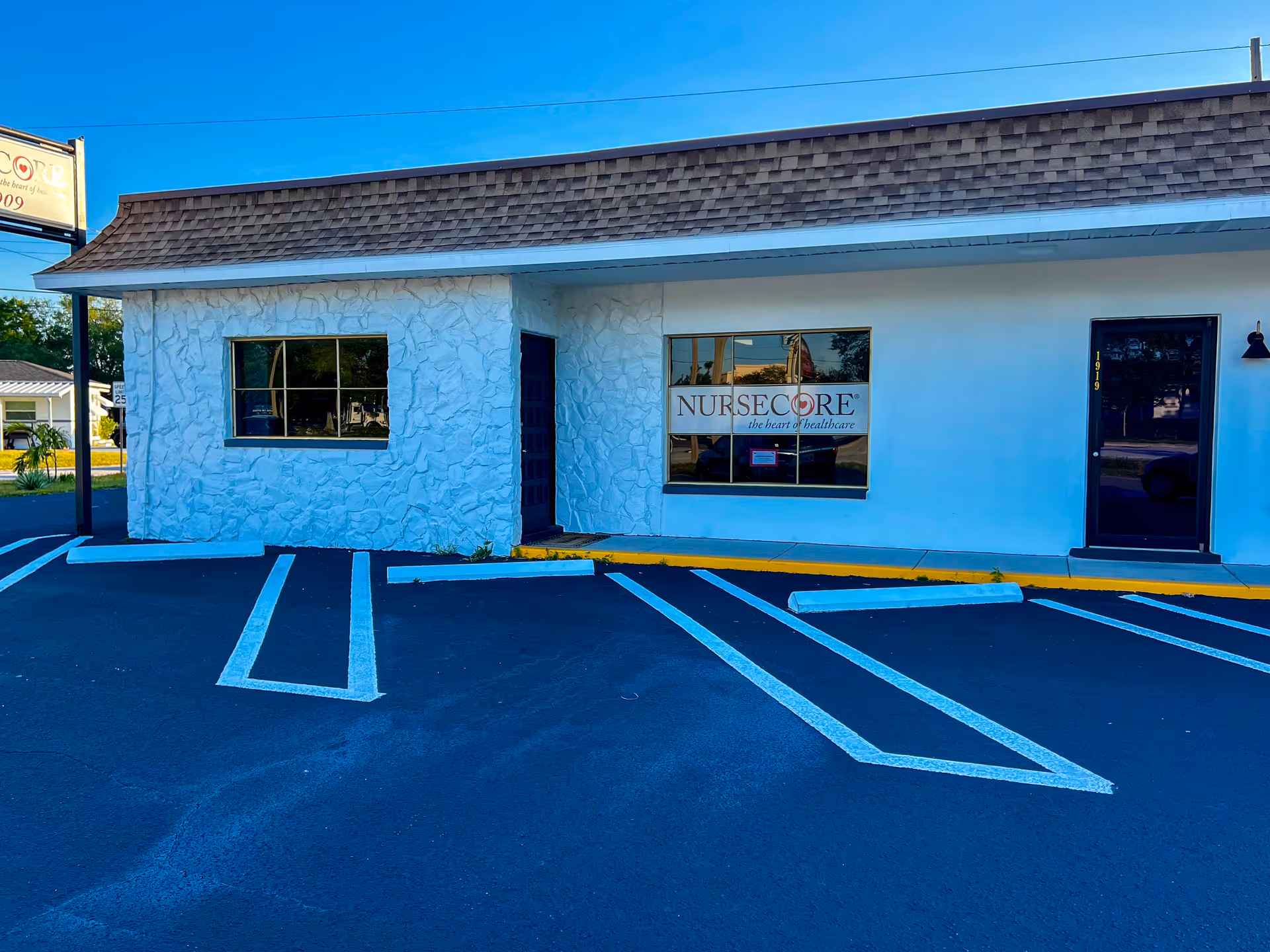 Blue-toned exterior of NurseCore facility with a parking lot in front.