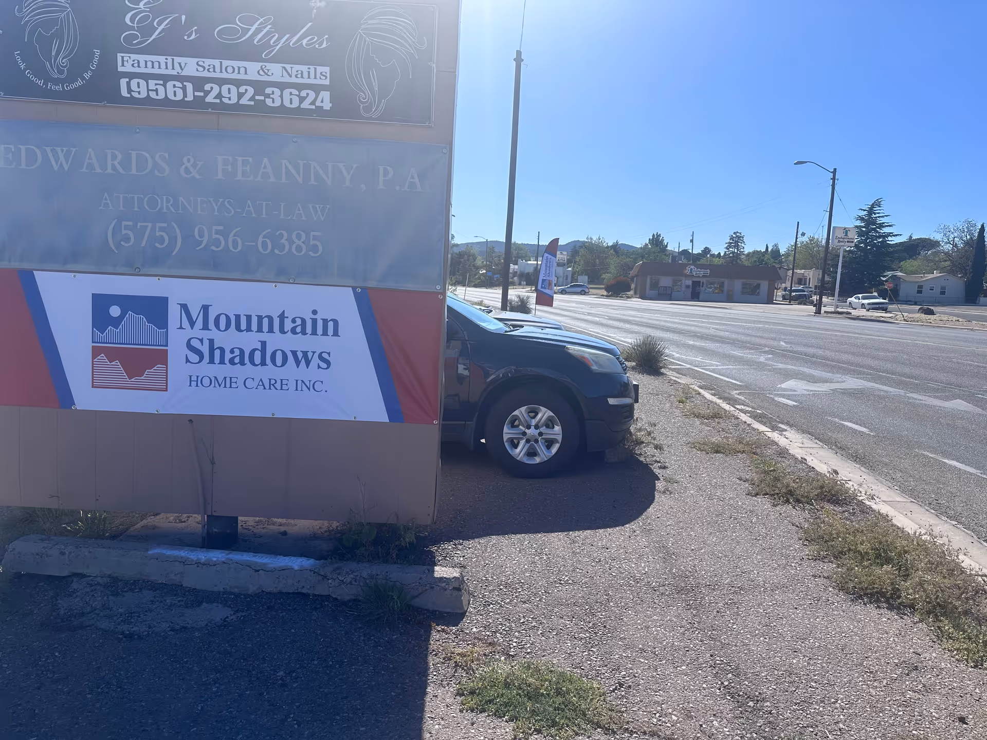 Roadside exterior with Mountain Shadows Home Care Inc. sign and a parked car.