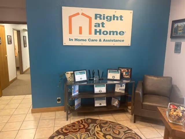 Teal-walled lobby with Right at Home sign, brochure shelf, chair, and patterned rug.