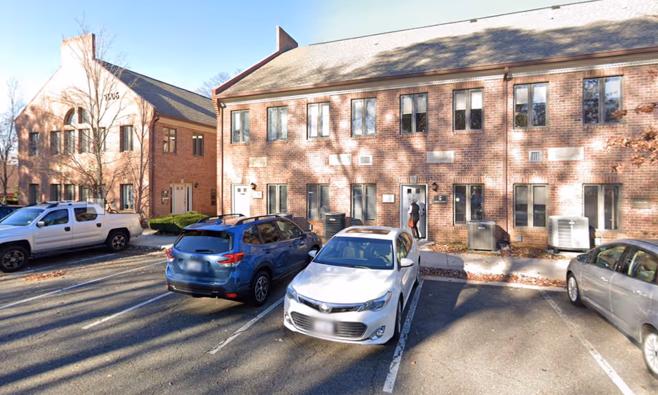 Exterior brick senior living building with multiple parked cars in front of entrances.