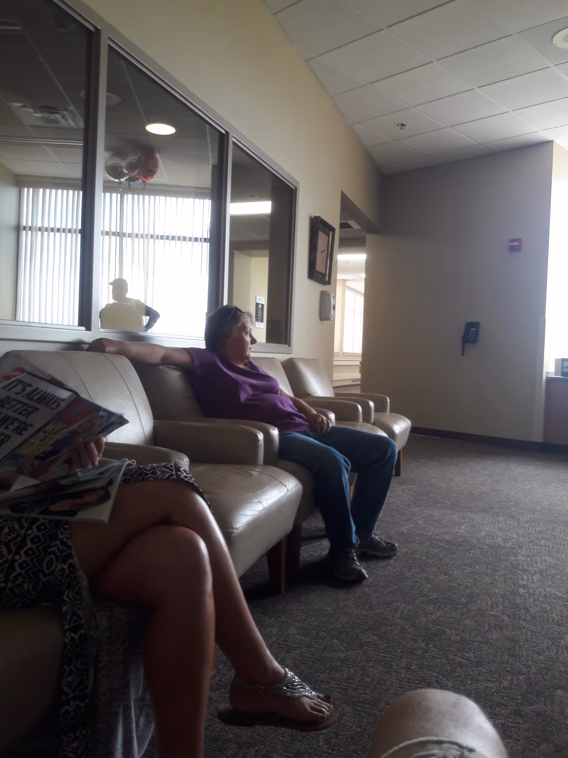 Two residents sit on beige couches in a neutral lounge area.