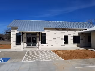 Front exterior of a single-story Enhabit Home Health facility with metal roof and ramp.