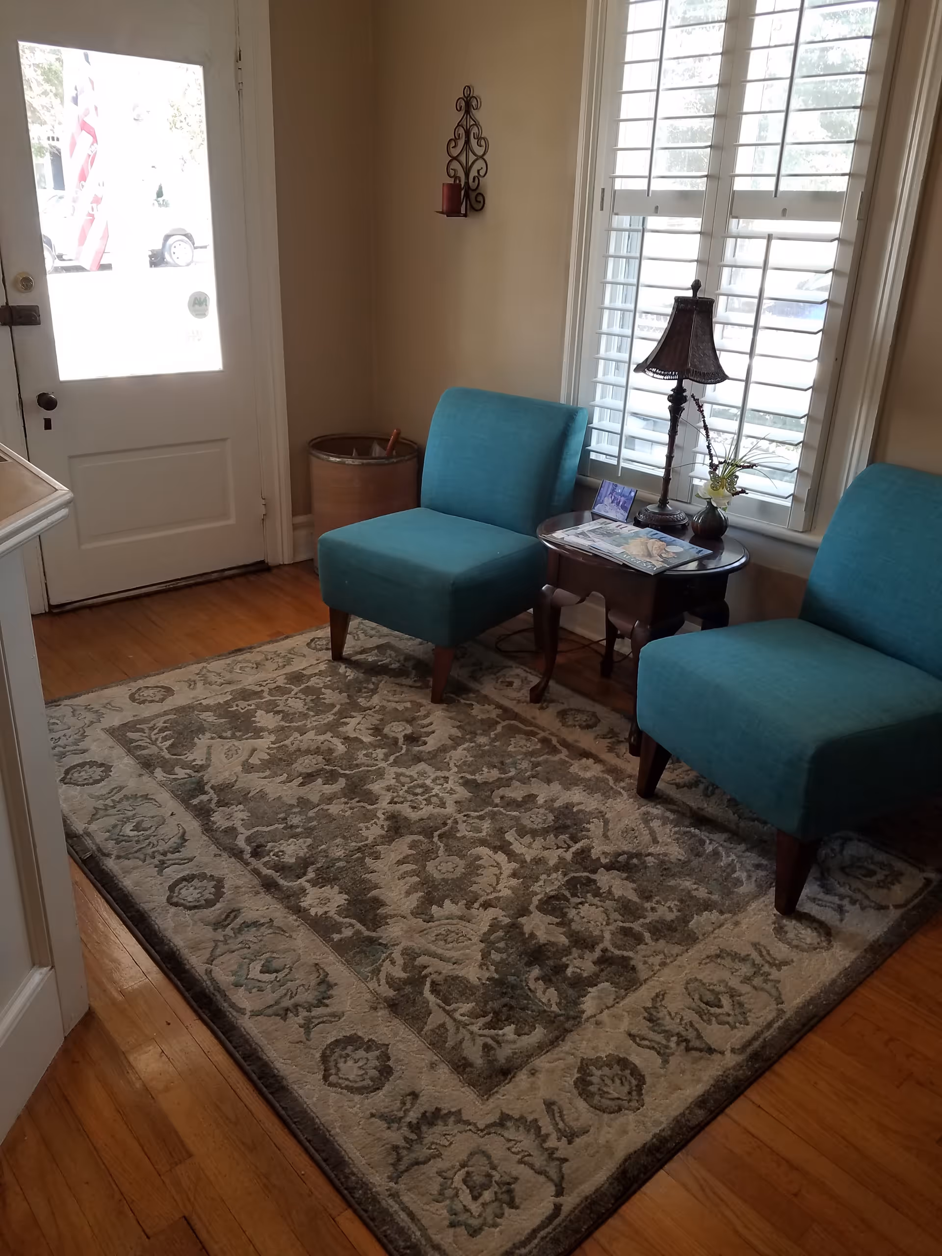 Two turquoise chairs flank a side table with lamp in a cozy living room.