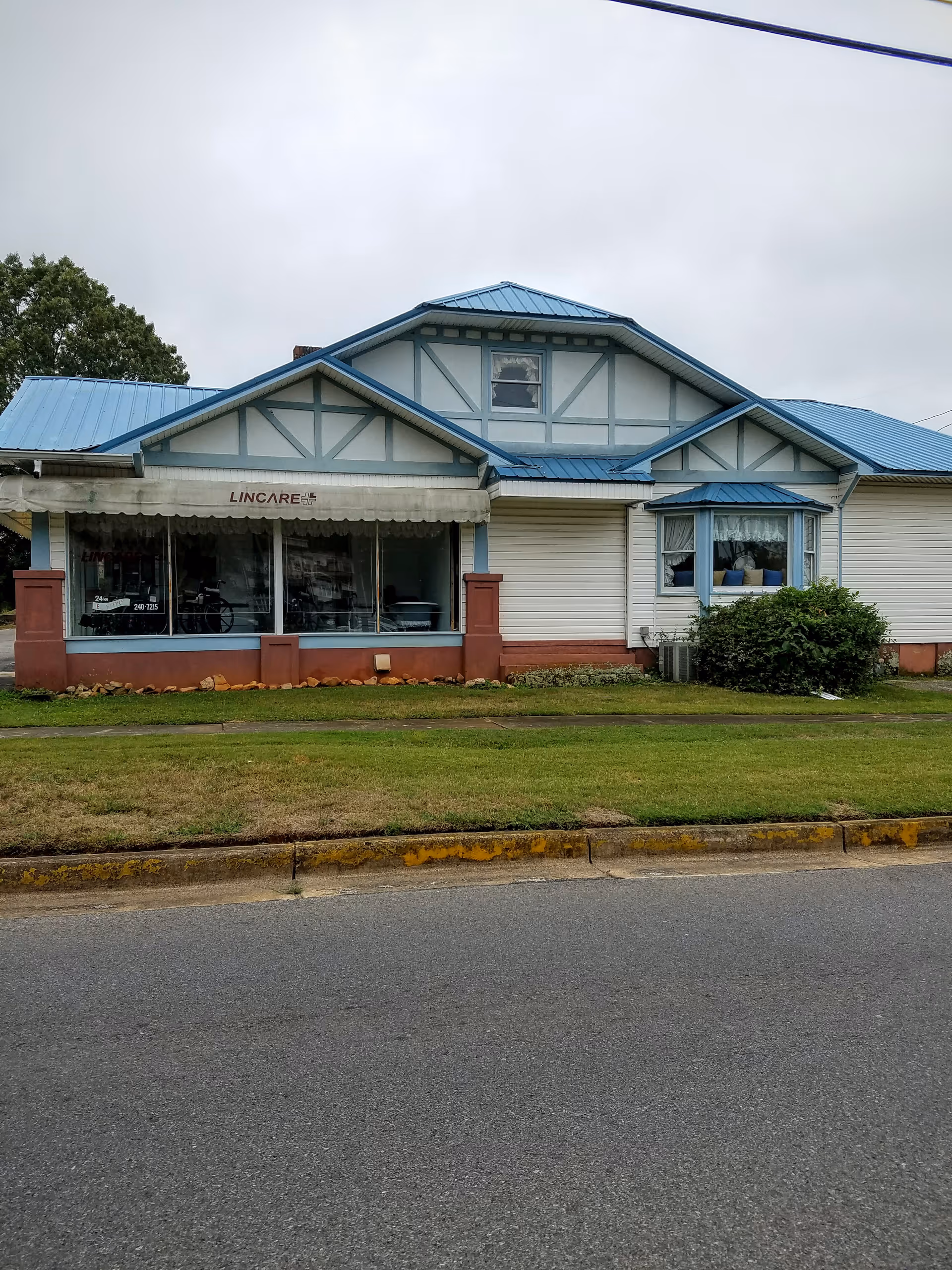 Single-story building with blue roof, storefront windows, and LINCARE sign at the front.