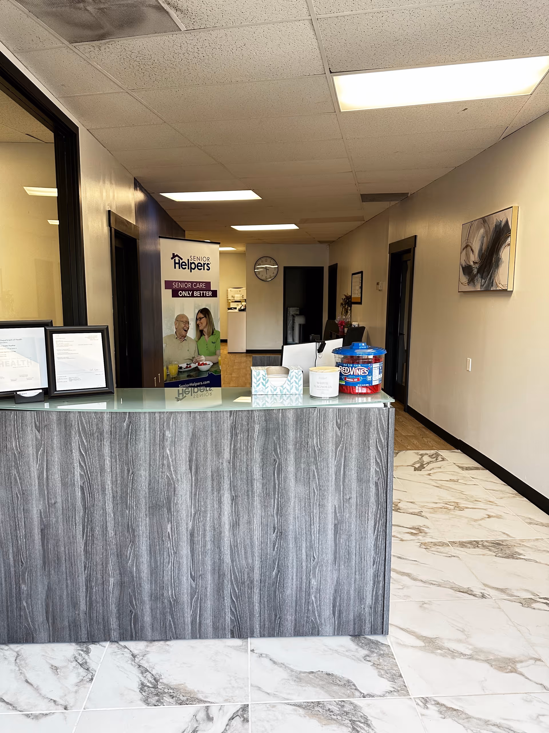 Reception desk in a Senior Helpers facility lobby with marble floor and signage.