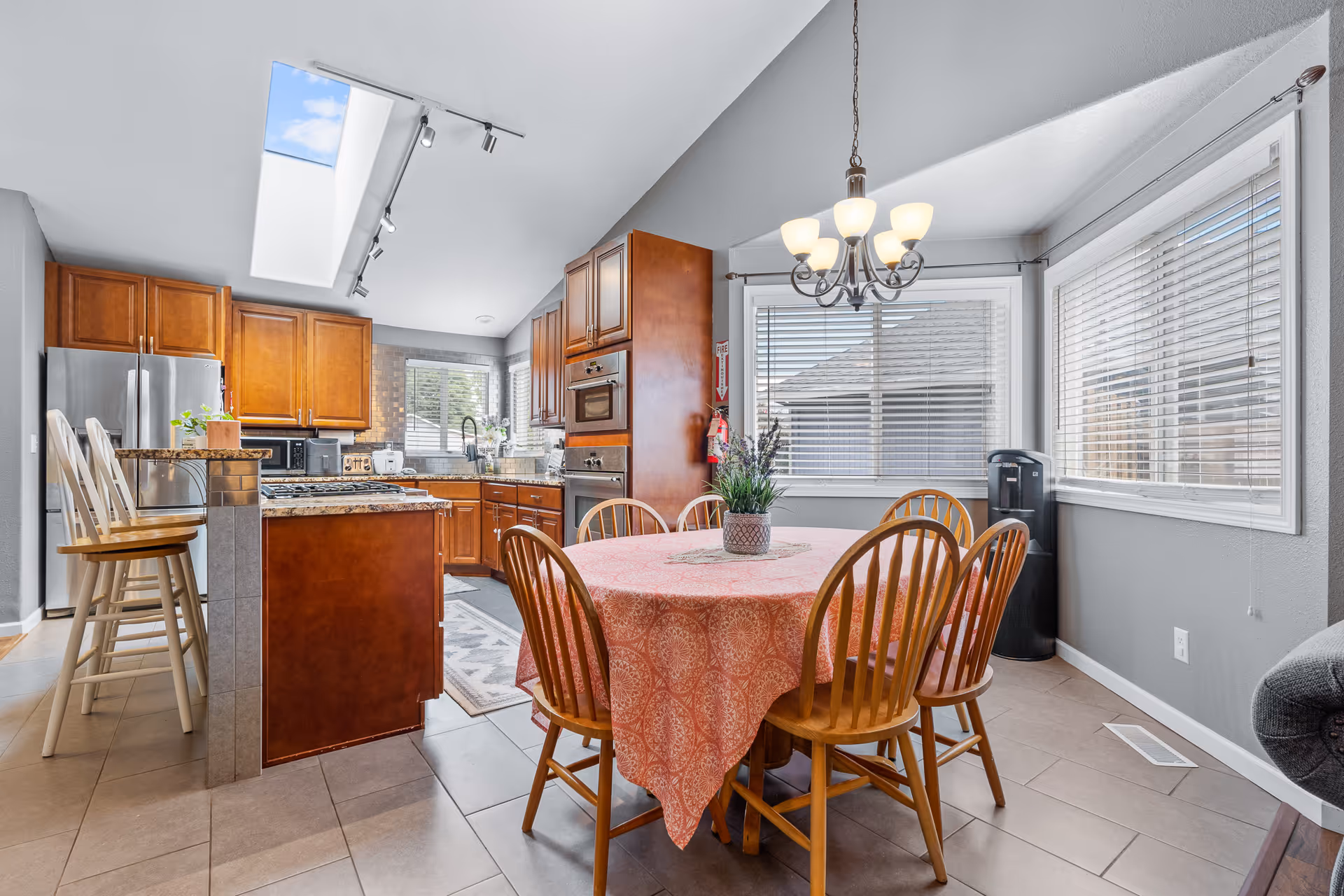 Bright open dining area with a round table, chairs, and a view of a kitchen island.