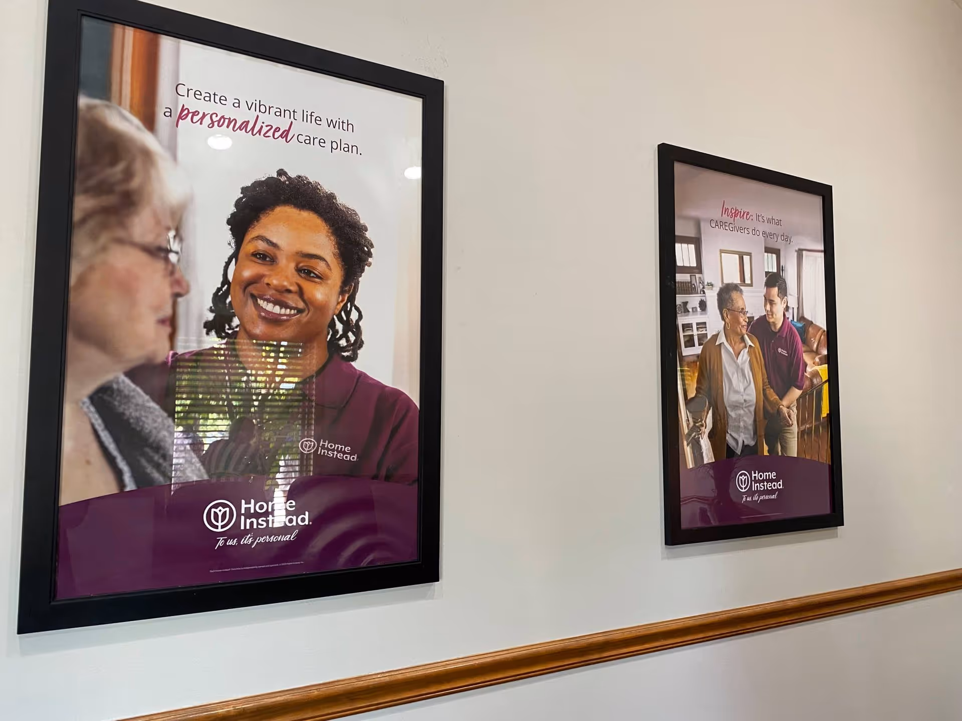 Hallway wall with two framed posters featuring smiling caregivers