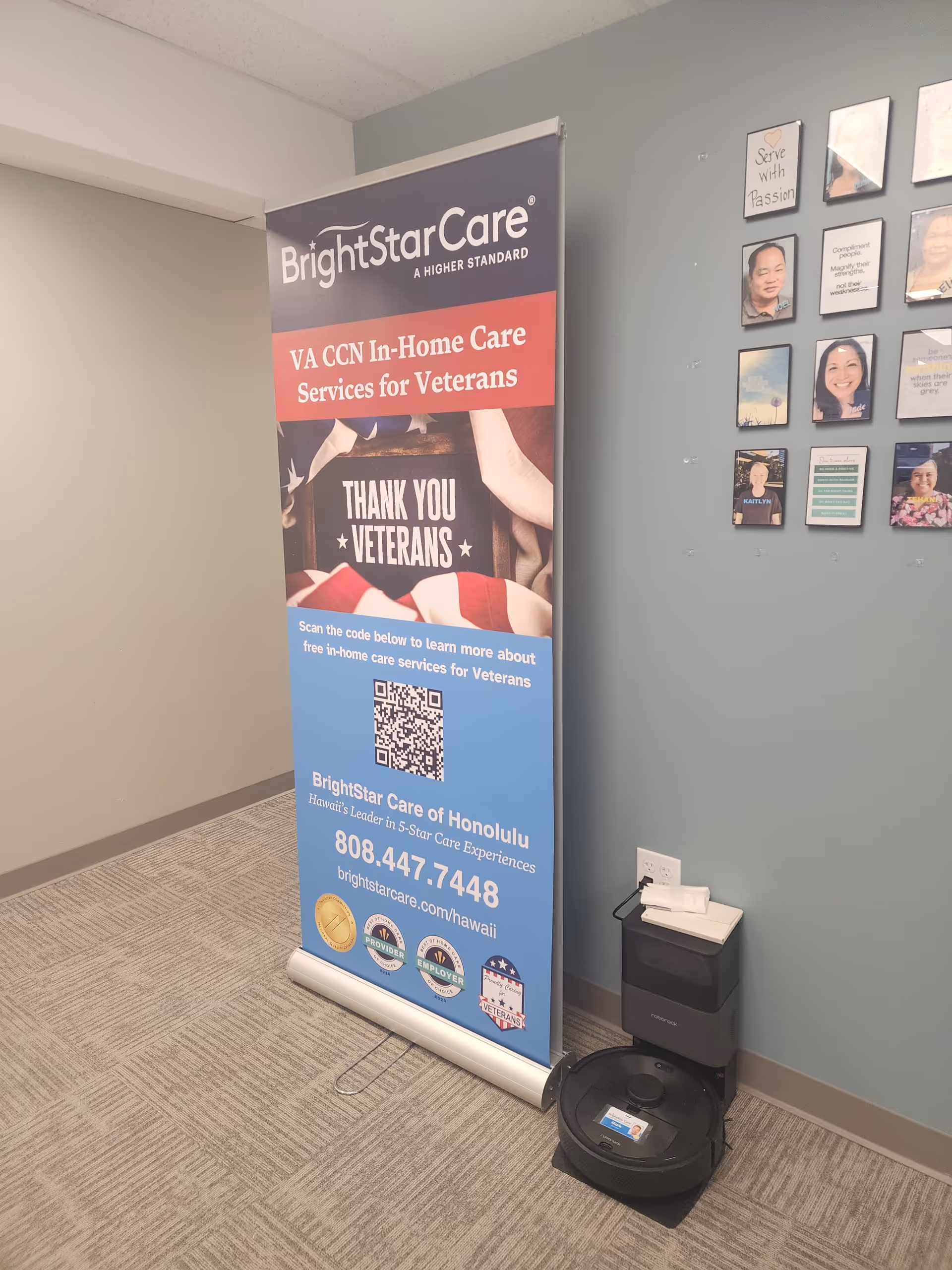 Tall BrightStar Care banner stands in a hallway beside a wall with framed photos.