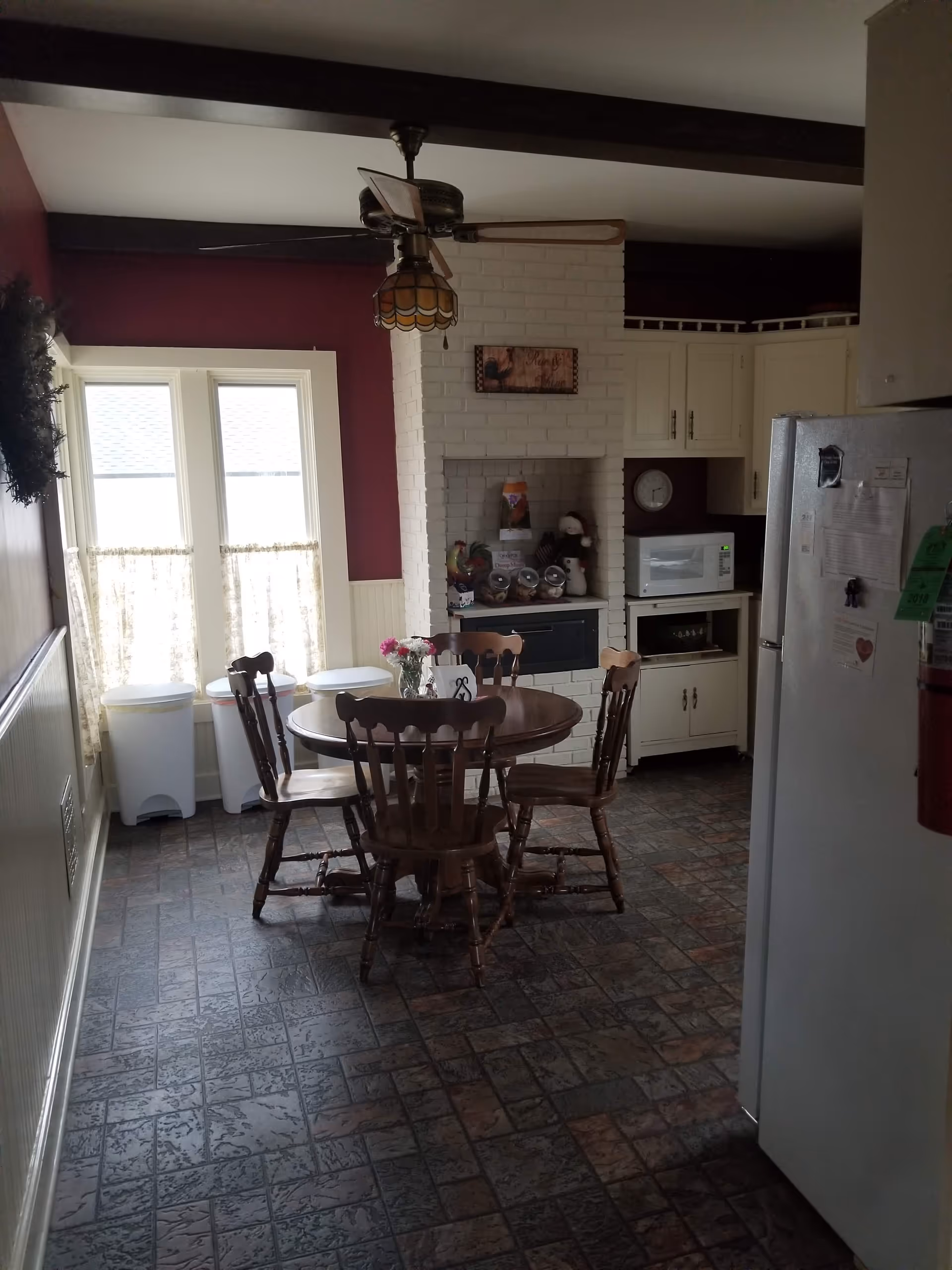 Wooden dining table with six chairs in a cozy kitchen and dining area near a fireplace.