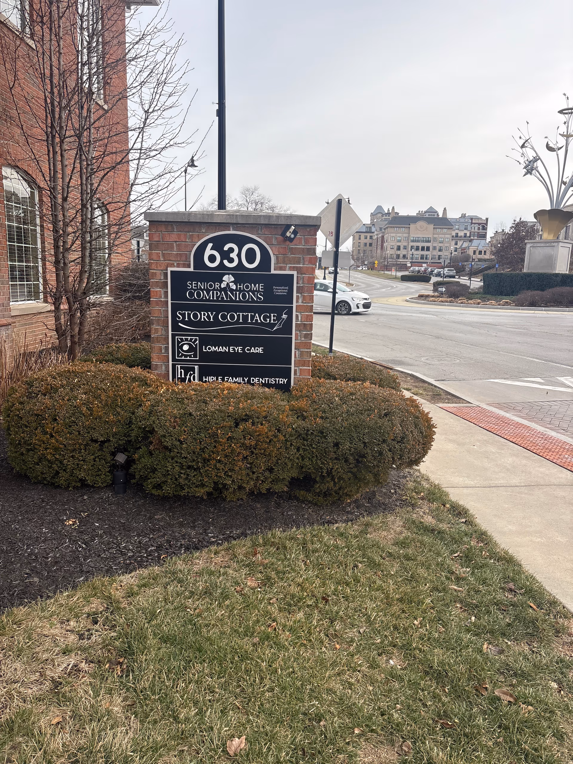Exterior scene with brick sign reading Senior Home Companions beside a sidewalk.
