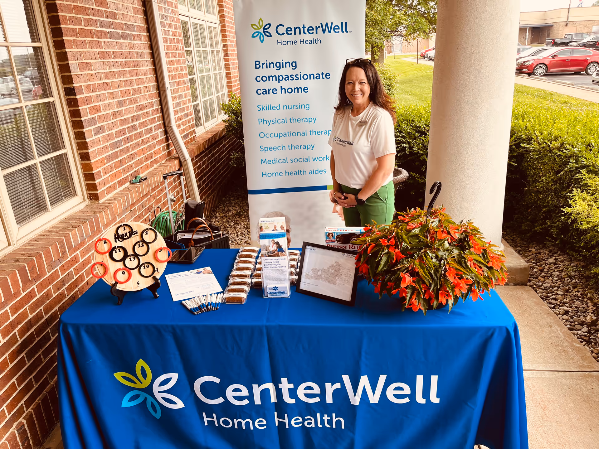 A CenterWell Home Health booth outside a brick building with a smiling staff member.