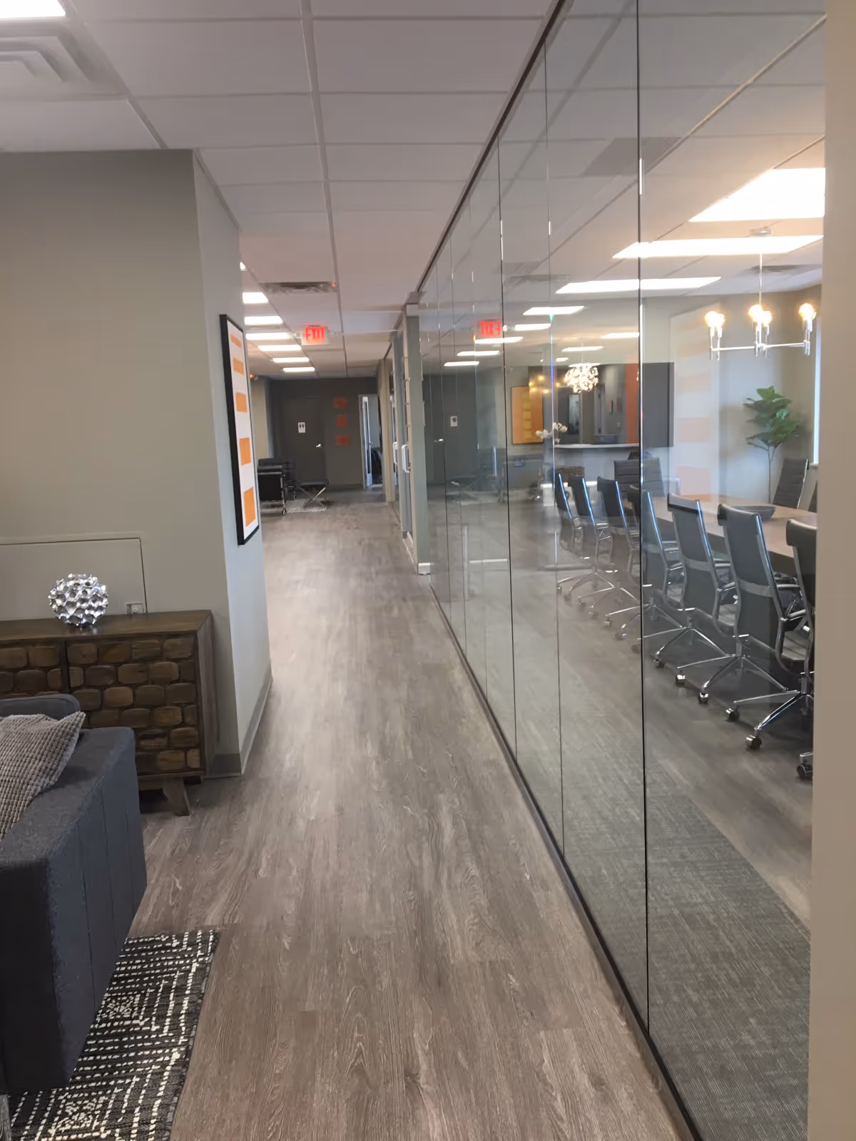 Long hallway inside a senior living facility with a glass-walled conference room on the right.