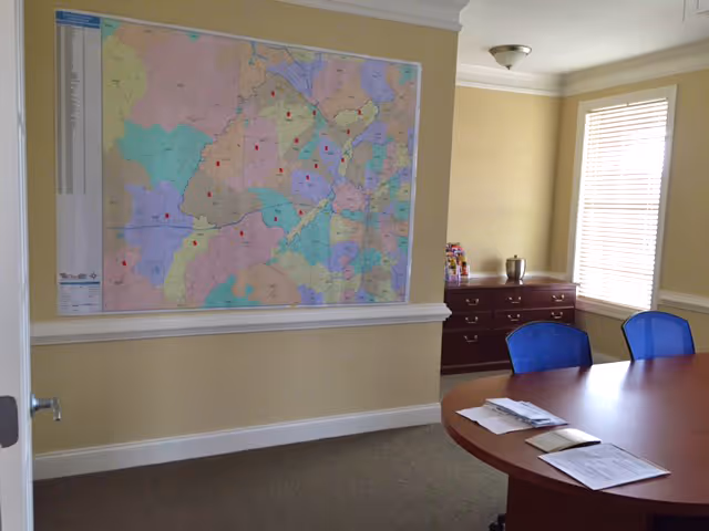 Map on wall in a sunlit conference room with a wooden table and blue chairs.
