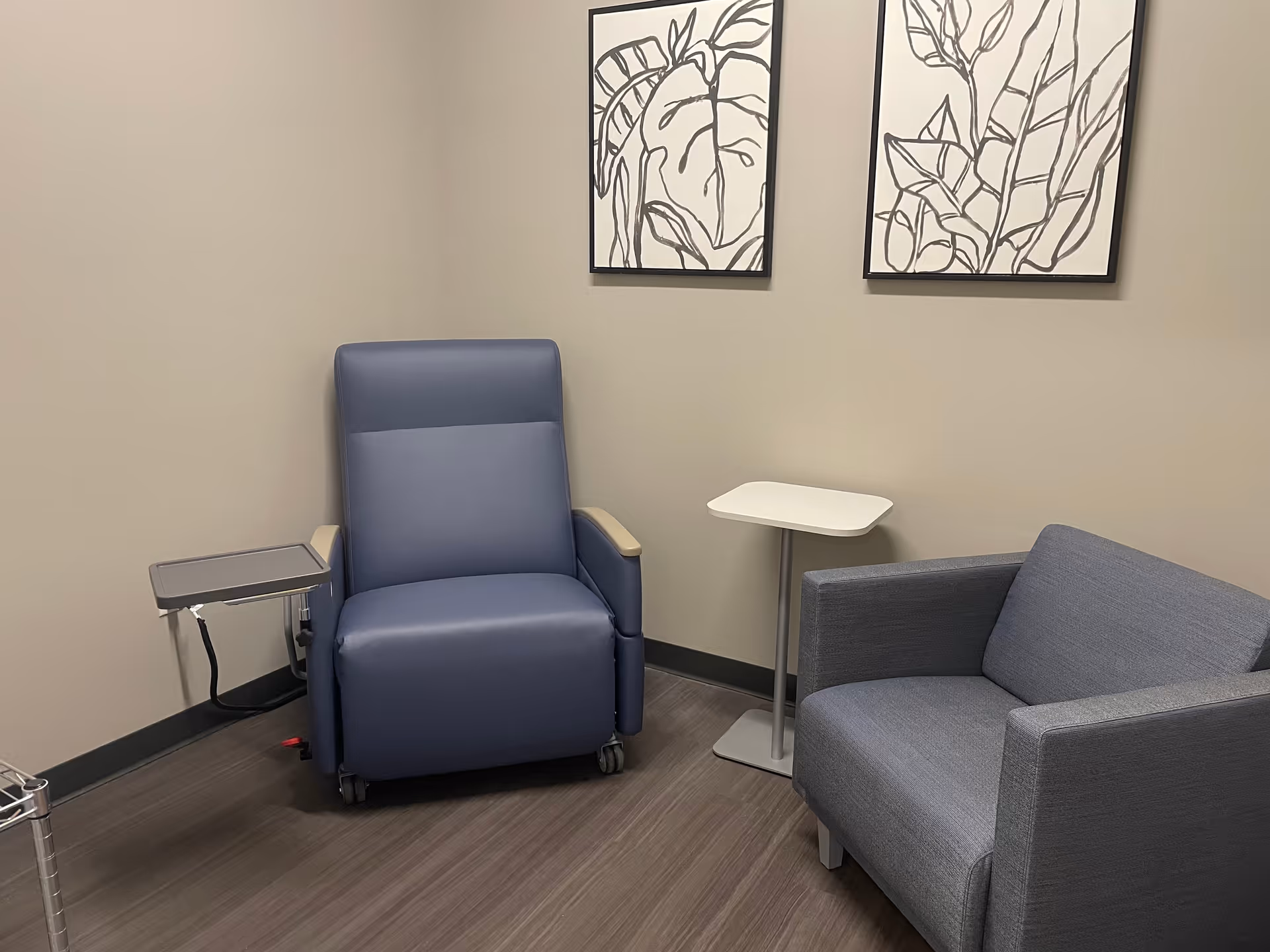 Small neutral lounge with a blue recliner, gray sofa, and framed abstract art.