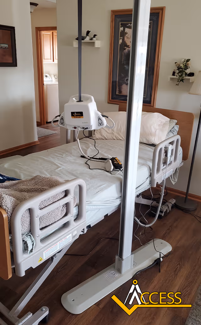 Hospital-style adjustable bed with ceiling lift in a resident bedroom.