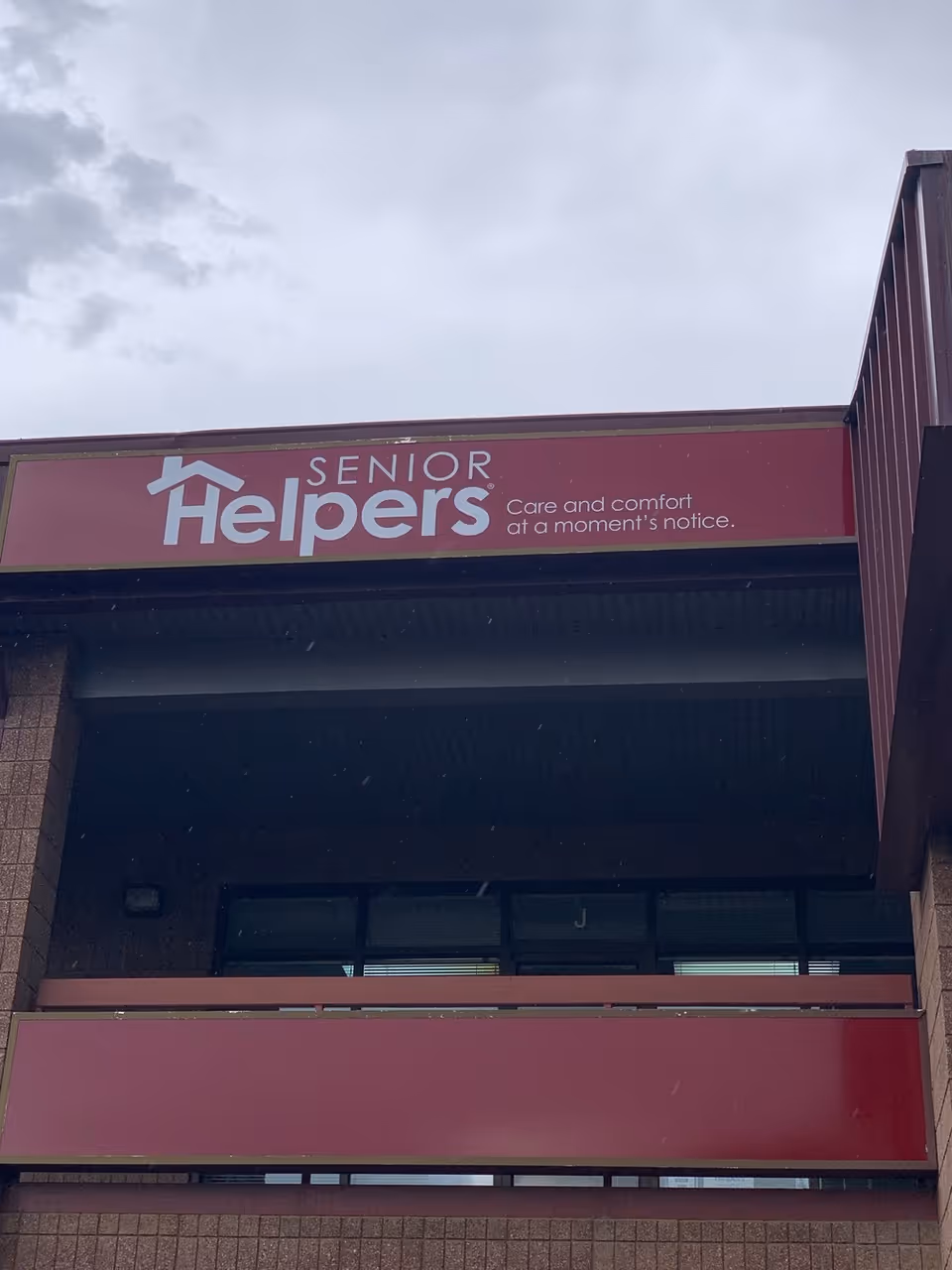 Front exterior of Senior Helpers facility with red sign above entrance.