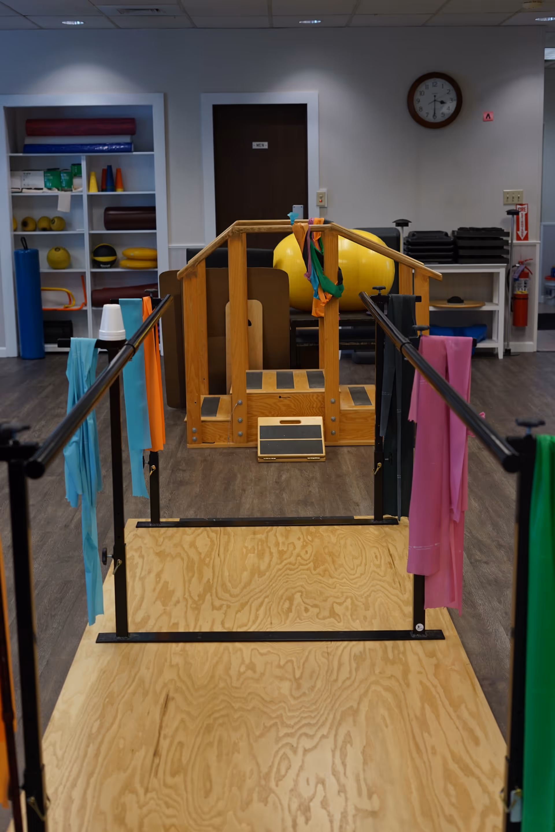 Indoor physical therapy room with parallel bars and gait training equipment.