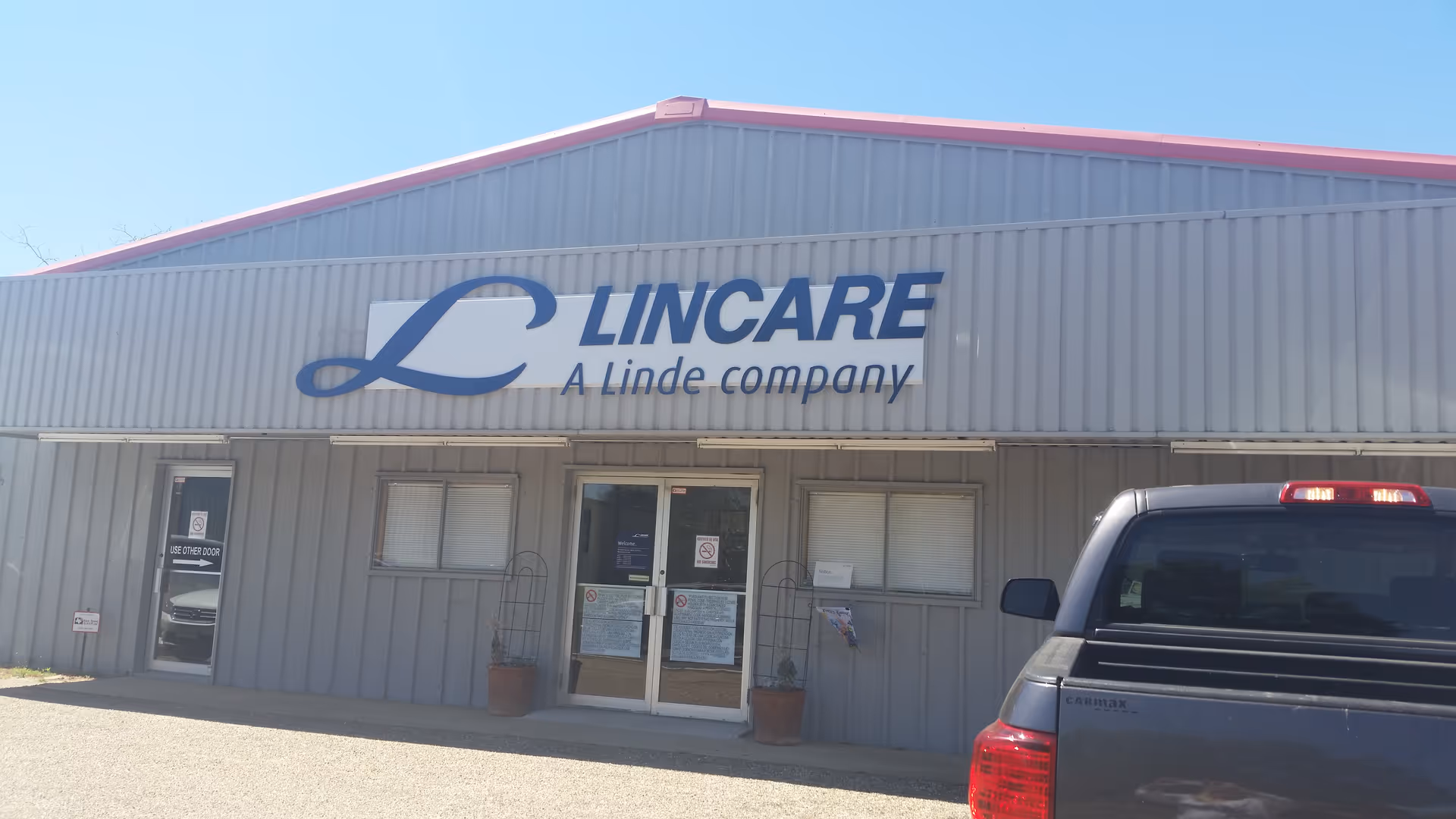 Exterior view of LINCARE building with large logo sign and a pickup truck parked outside.