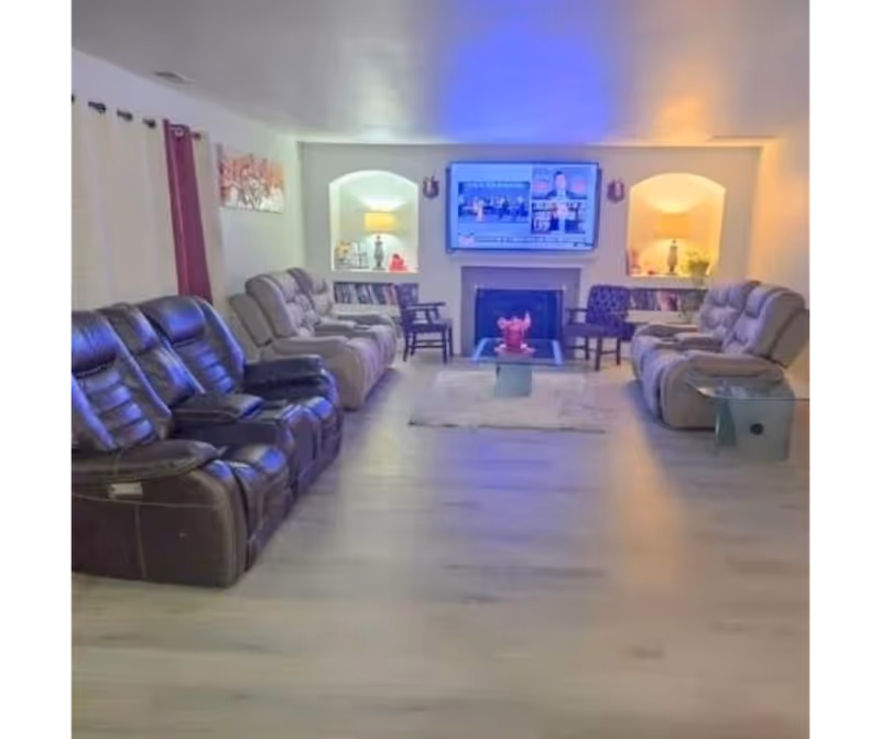 Spacious living room lounge with multiple recliners arranged around a central table and wall TV.