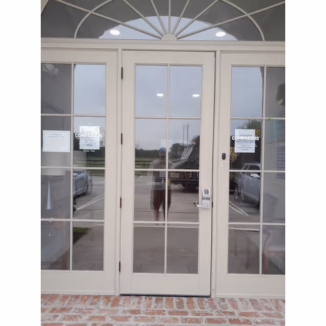 Compassus building entrance with glass doors, brick threshold, and reflections.