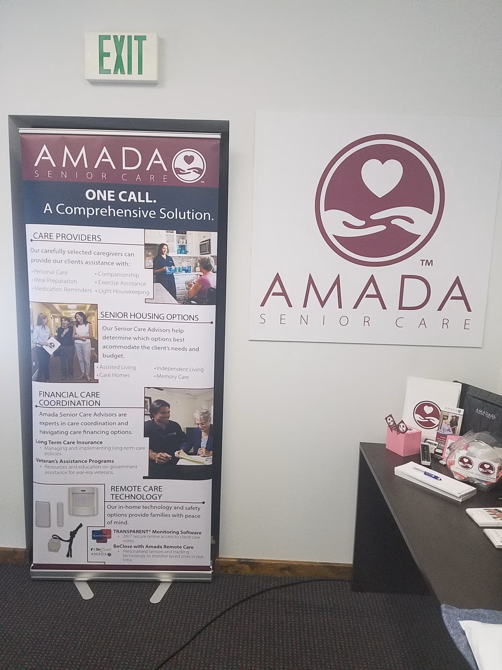Interior corner shows Amada Senior Care banners and a reception desk with brochures.