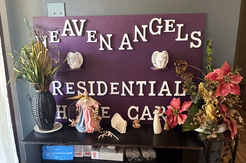 Purple sign reads Heaven Angels Residential Home Care with decorative figurines and flowers.