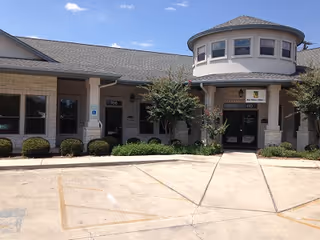 Front view of a beige senior living facility with a curved turret and entrance doors.