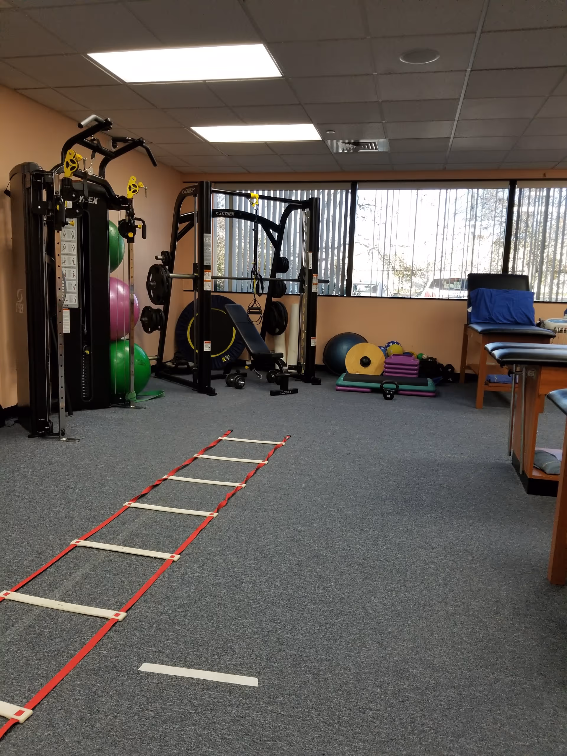 Interior senior fitness room with weight machines, therapy balls, mats, and an agility ladder.