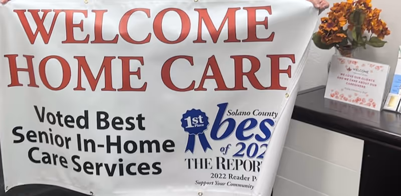 Large interior banner reading Welcome Home Care with awards beside a flower arrangement.