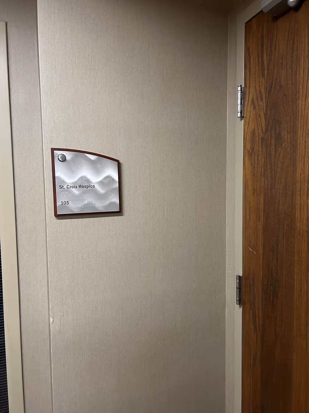 Interior hallway with a St. Croix Hospice plaque beside a wooden door.