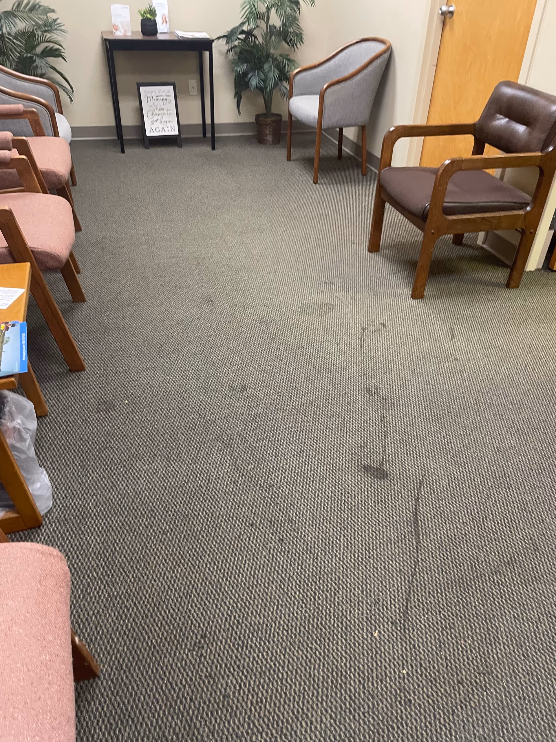 A waiting area with chairs, plants, and a small table inside a LINCARE facility.