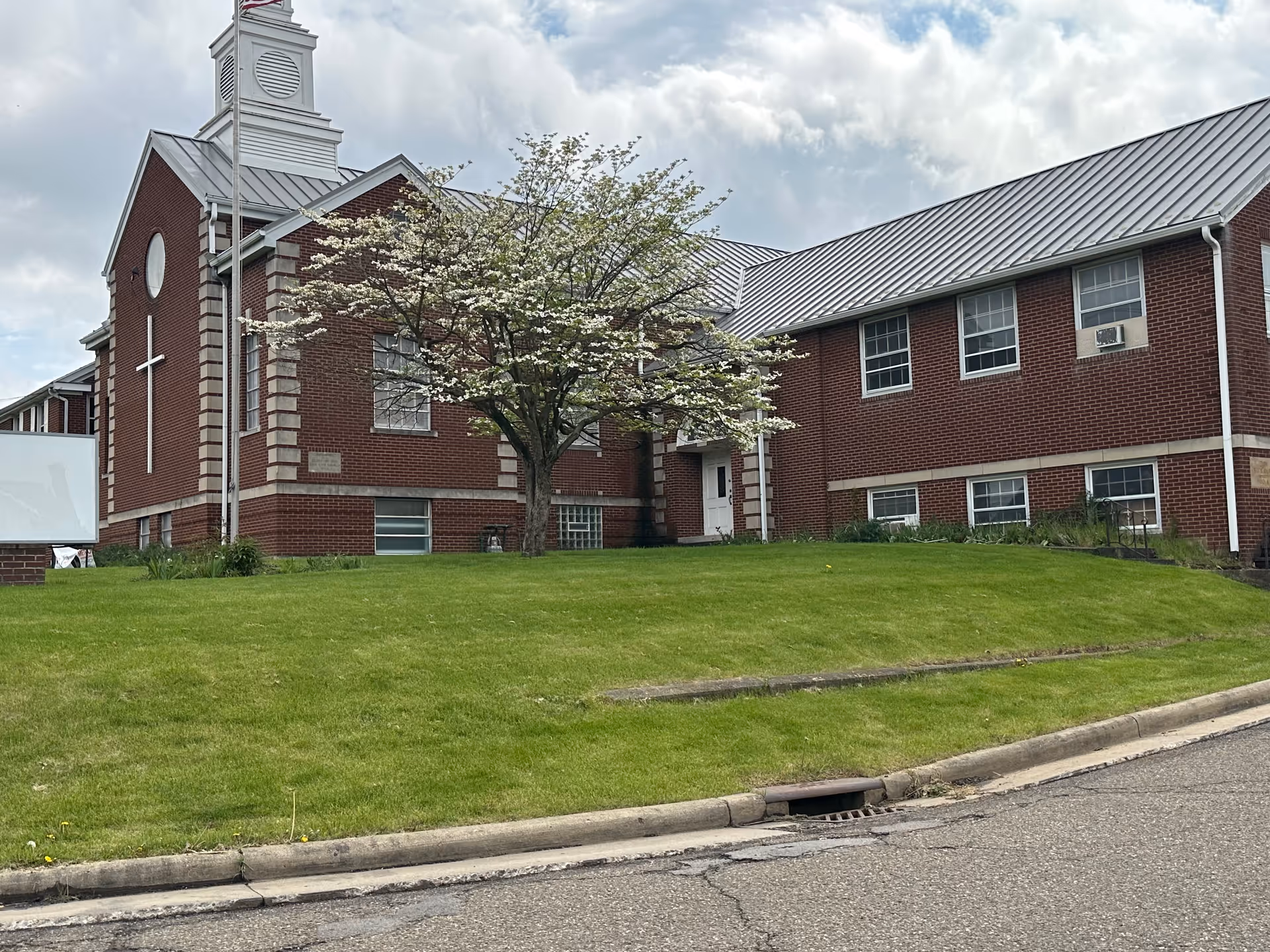 Brick senior living facility exterior with a blooming tree and green lawn.